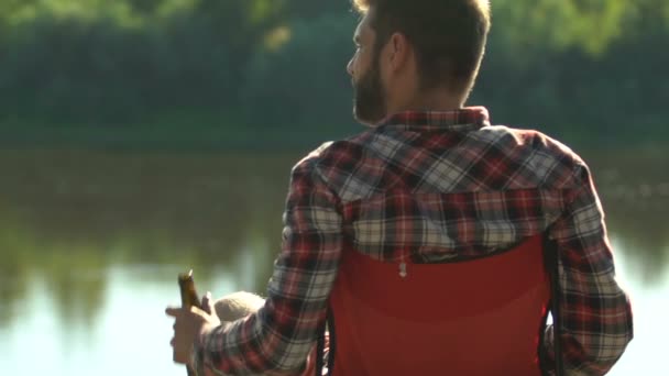 Homem Relaxado Sentado Perto Lago Bebendo Cerveja Engarrafada Piquenique Recreação — Vídeo de Stock
