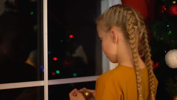 Solitaire fille accrocher ballon sur arbre de Noël à l'orphelinat, penser à la famille 