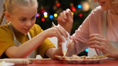 Küçük kız gingerbread krema şeker, Büyükanne hugs ve övgü ile dekorasyon