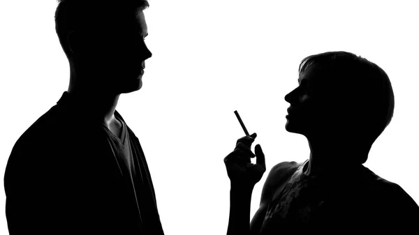 年轻女性拿着香烟和与男人调情的剪影 — 图库照片