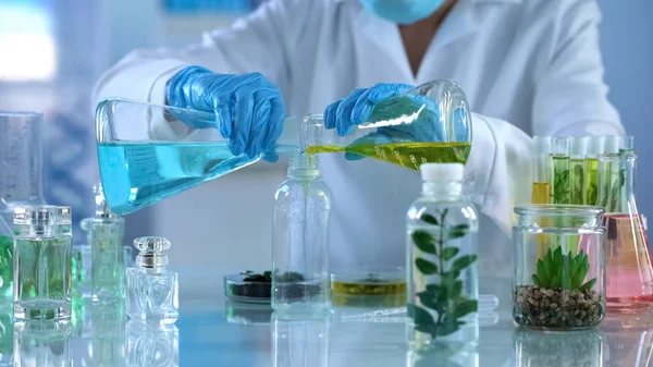 Researcher mixing liquids in bottle, new perfumes development, organic aroma
