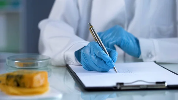 Lab technician writing down analysis results, quality of food, nutrition