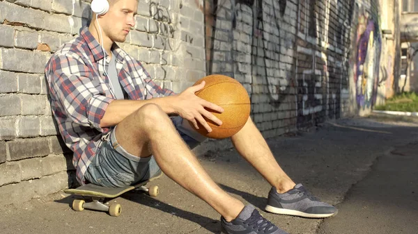 Doordachte Mannelijke Tiener Zittend Een Skateboard Luisteren Naar Muziek Hoofdtelefoons — Stockfoto