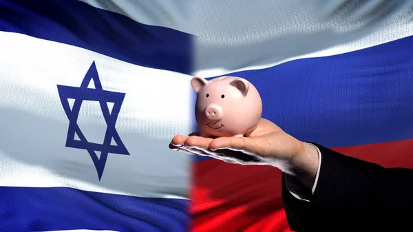 Israel Investitionen Russland Geschäftsmann Hand Hält Sparschwein Flagge Hintergrund — Stockfoto