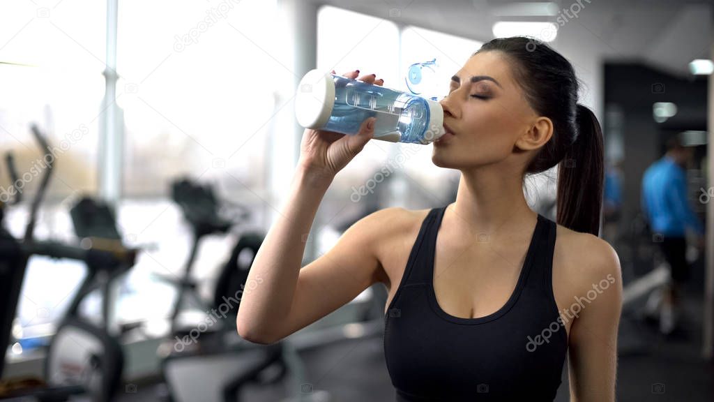 Sport lady drinking water after gym training, aqua balance, healthy nutrition