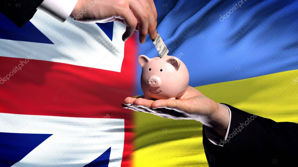 Great Britain investment in Ukraine hand puts money in piggybank flag background