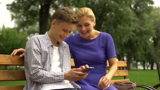 息子と母のベンチ見てスマート フォンの写真撮影中に座って歩く — ストック動画