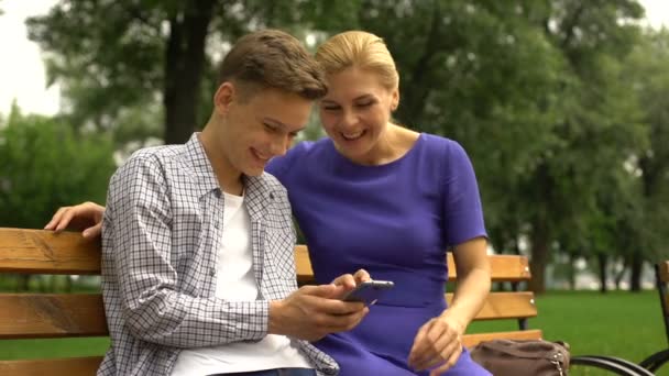 Hijo Madre Sentados Banco Viendo Fotos Teléfonos Inteligentes Tomadas Durante — Vídeo de stock