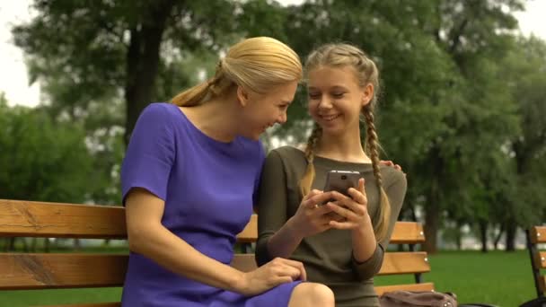 女儿和母亲笑着 在智能手机上散步时观看他们的照片 — 图库视频影像