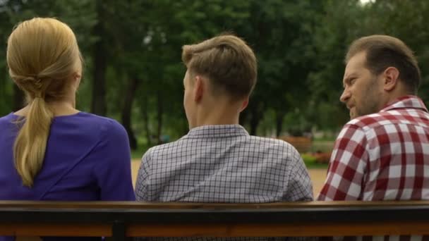 十几岁的儿子和父母坐在板凳上谈论假期 — 图库视频影像