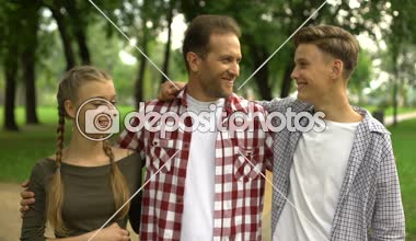 Neşeli aile sarılma ve kamera Park, güvenilir bir ilişki içine gülümsüyor