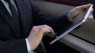 Lüks arabada oturan genç başarılı iş adamı tablete, zor iş çalışma