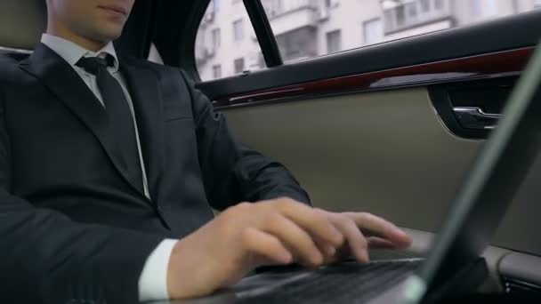 自信を持ってビジネスの男性車で後部座席に座っていると 仕事のプロジェクトのノート パソコンを使用して — ストック動画