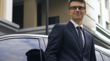 Arabanın yakınında duran ve mutlulukla gülümsüyor, başarılı anlaşma emin işadamı