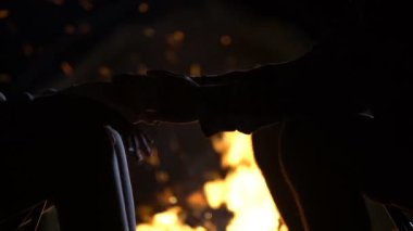 Adam kız elini tutarak şenlik ateşi, romantik aşk itirafı, gece karşı