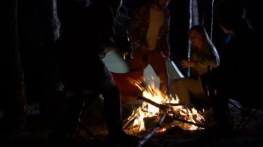 Arkadaş grubu gece şenlik ateşi, çevresindeki sandalyelere oturan bira şişeleri ile