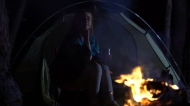 Genç tek oturan Bayan ve düşünceli yangın alevler seyir sıcak içecek