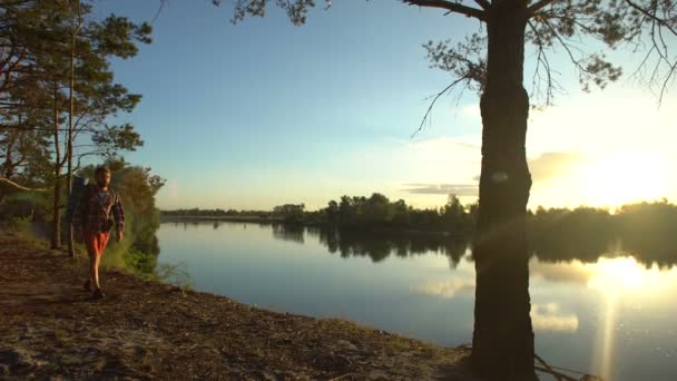 美しい景色を楽しみながら 壮大な場所で川の土手に沿って歩くハイカー — ストック動画