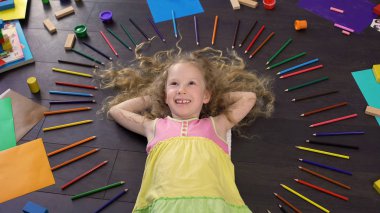 Yerde yatarken ve tatil hakkında rüya gülümseyen sarı saçlı küçük bir kız