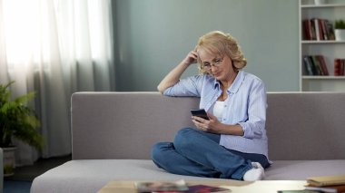 Çok üst düzey kadın kanepe ve hesaplama bütçe üzerinde oturan Smartphone kullanarak