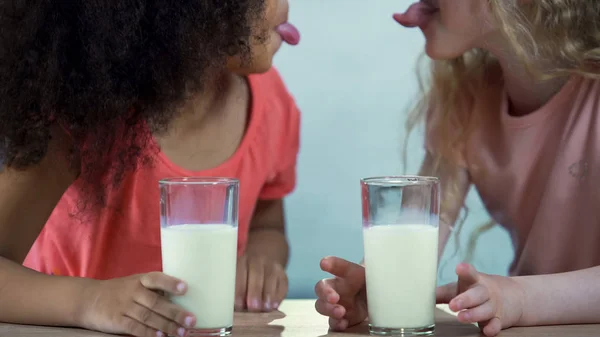 Счастливые Многонациональные Дети Держащие Стаканы Молока Показывающие Язык Друг Другу — стоковое фото