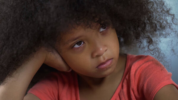 Lonely sad African American girl sitting at table, racism and bulling at school