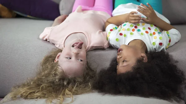 Mutlu çocuklar eğleniyor dil melez arkadaşına gösterilen kız kanepe, yalan