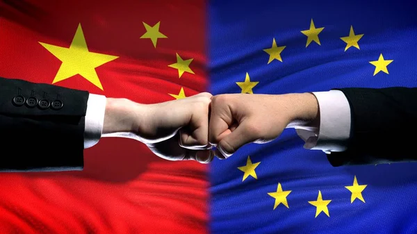 China vs EU conflict, international relations crisis, fists on flag background