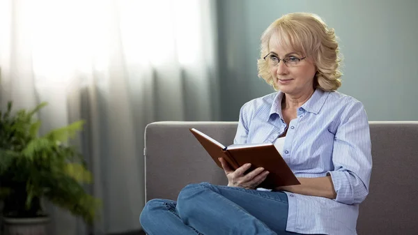 ソファーに座っていた本では 自由な時間退職趣味中年の主婦 — ストック写真