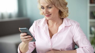 Gülümseyen yaşlı Bayan fotoðraf akıllı telefon, sosyal ağ iletişimi arıyorum