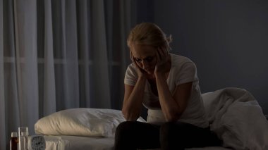 Yorgun orta yaşlı kadın yatakta oturuyordu gece uykusuzluk hastalığı, sorun