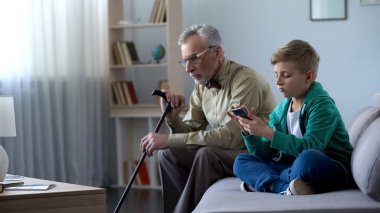 Grandson using smartphone, upset granddad sitting aside, internet addiction clipart