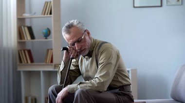 Gülümseyen yaşlı adam üzerinde baston, eğilerek şekerleme yemekten, sağlıklı alışkanlık sonra