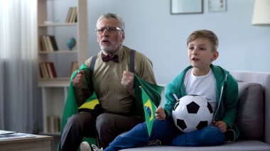 Çocukla futbol izlerken, oyun hakkında endişelenmeyi Brezilya bayrağı sarılı Büyükbaba