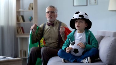Çocukla futbol izlerken, oyun hakkında endişelenmeyi Portekiz bayrağı sarılı dede