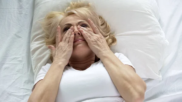 Blond Senior Vrouw Aanraken Van Haar Gezicht Liggend Bed Masker — Stockfoto