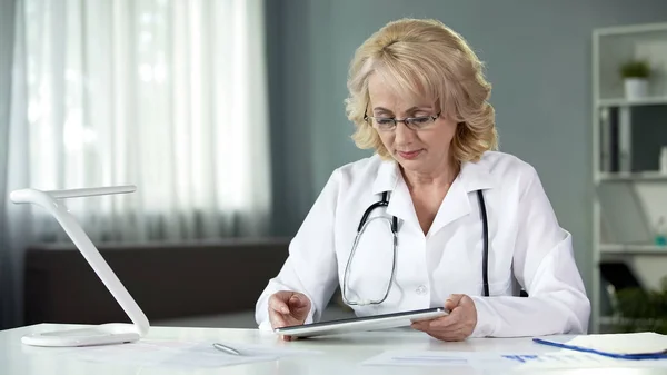 Female General Practitioner Reading Patient Online Medical Records Tablet — Stock Photo, Image