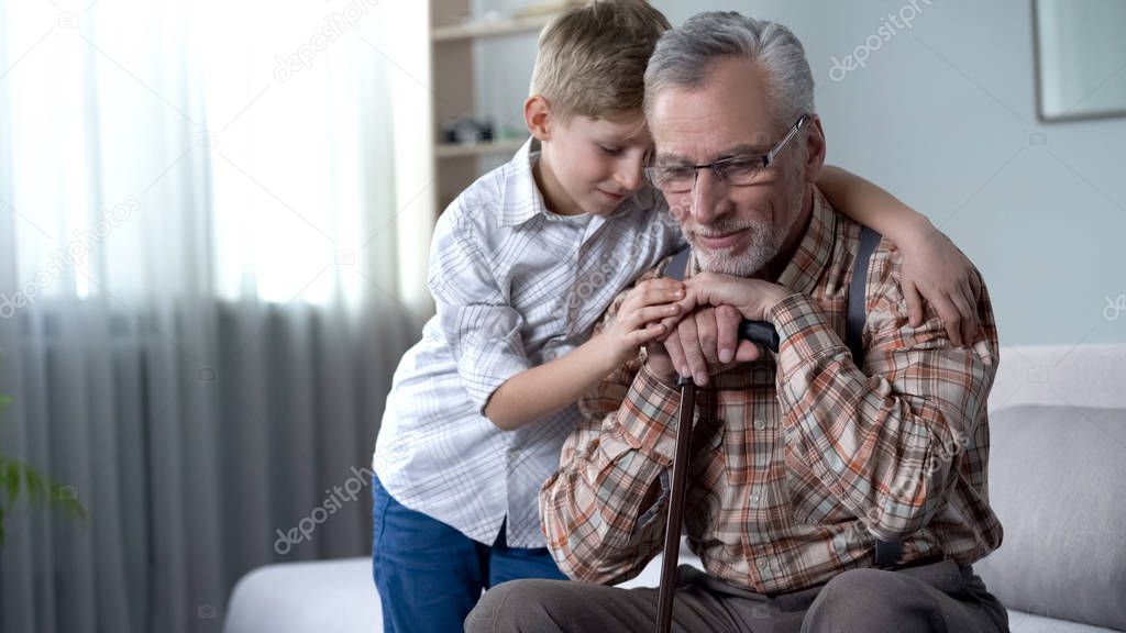 Boy comforting old lonely man, embracing him, charity program in nursing home