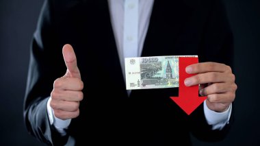 Yaşasın, düşen ok gösterilen Rus Rublesi banknotlar tutan işadamı