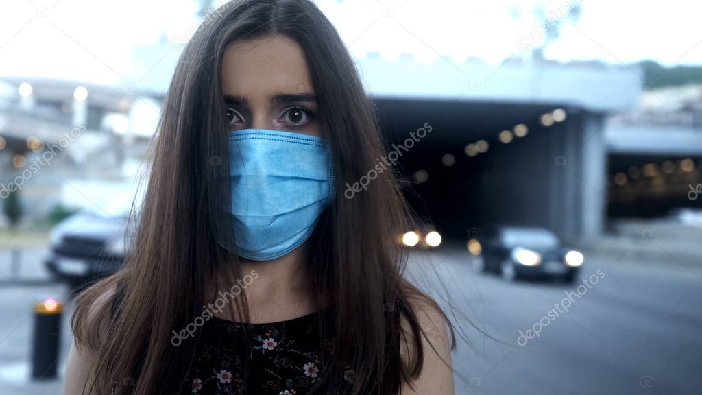 Lady in protective mask in big city, air pollution, epidemic or airborne disease