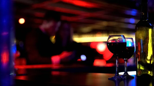 ボトルの つのワイングラスでバー ナイトクラブでのカップル背景をぼかした写真 — ストック写真