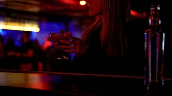 Elegant woman drinking cocktail in bar alone, enjoying music, relaxed atmosphere