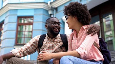 Kız ve erkek arkadaşı oturma merdiven, birlikte, eğleniyor kentsel tarihi açık