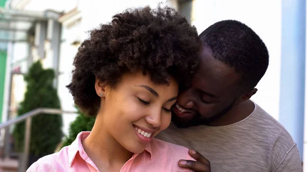 彼氏の腕の中 笑みを浮かべて安全な感じの女の子を楽しんでいるアフリカ系アメリカ人のカップル — ストック写真
