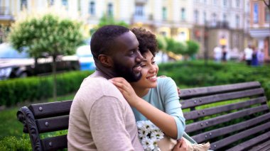 Çift bankta kucaklayan sevgi dolu, beyaz çiçekler, yaz günü birlikte zevk