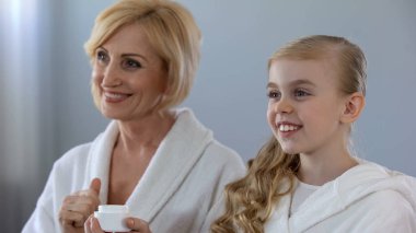 Büyükanne ve gülümseyerek, parlak deri krem sonra güzellik zevk torunu