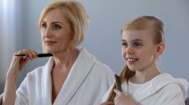 Olgun erkek ve Genç saç tarama ve aynanın önünde gülümseyen