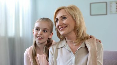 Küçük kız ve mutlu bir şekilde sarılma ve yüzüne, büyükannesi aile içinde bakım