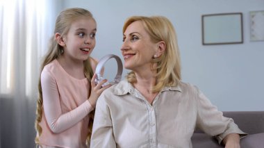 Büyükanne, eğleniyor şirin küçük torun holding kulaklıklar, sakin ol