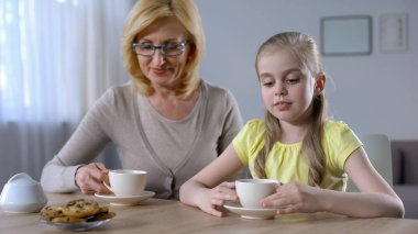 Büyükanne ve sevimli küçük kız çerezler, aile gelenekleri ile çay içme